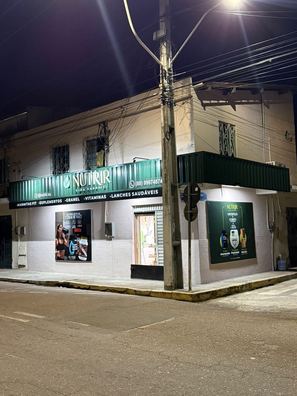 Fachada da Nutrir Vida Saudável à noite, com o letreiro iluminado na esquina da Rua Caetano Figueiredo, na Cohab I, em Sobral
