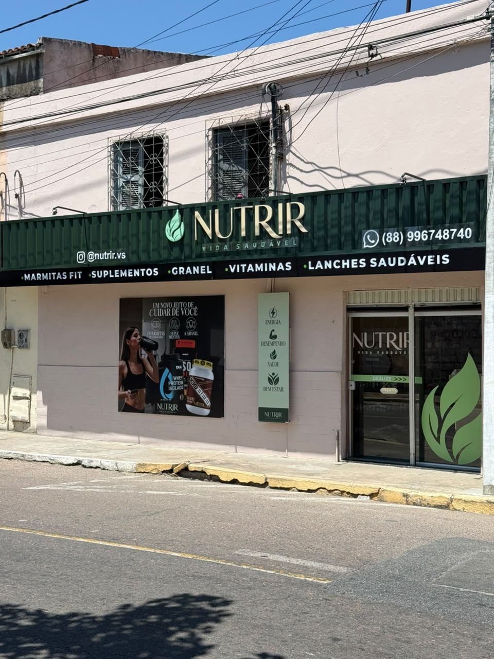 Fachada da loja Nutrir Vida Saudável na esquina da Rua Caetano Figueiredo, na Cohab I, em Sobral, com o toldo verde e a lista de categorias